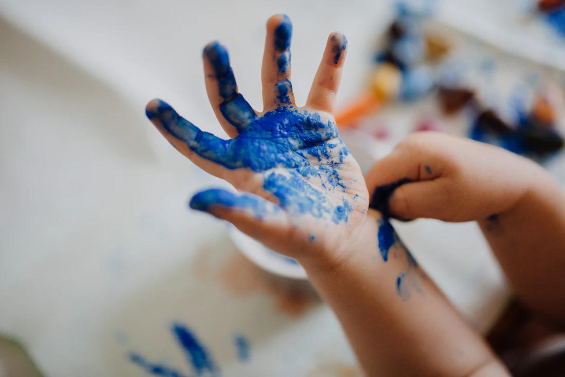 Little hands exploring blue paint, an illustrative image of creative play